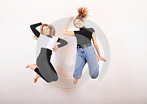 Two teenage girls smiling and jumping friends