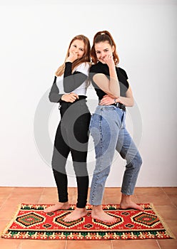 Two teenage girls standing on oriental carpet