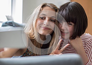 Two Teenage Girls Taking Selfie In Bedroom At Home