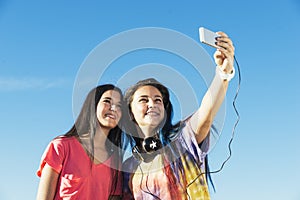 Two Teenage Girls Taking Selfie In Park