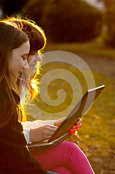 Two teenage girls working on notebook in the park