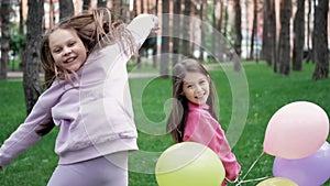 two teenage school girls having fun outdoors. in colourful clothes near hot air balloons. friendship, sisterhood