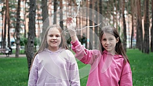 two teenage school girls having fun outdoors. in colourful clothes near hot air balloons. friendship, sisterhood