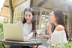 Two teenage women meet in coffee shop use laptop together in aft