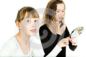 Two teenaged girls, one with Two teenaged girls, one with braces, in puberty age haggle to get a mirror to make a make up haggle