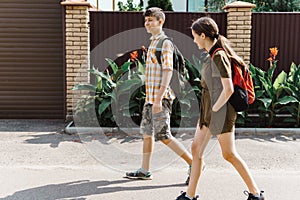 Two teenagers boy and girl going down the street to school, education and back to school concept