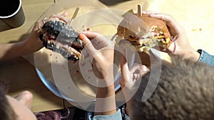 Two teenagers eating burgers in a cafe. Top view