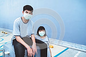 Two teenagers, a man and a woman, wear masks outside the building to prevent COVID-19 infection. Wear a mask to prevent virus infe