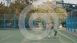 Two teenagers throw a ball into a basketball basket at a lesson at school