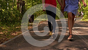 Two teens girls friend walking in park together holding hands, legs closeup.