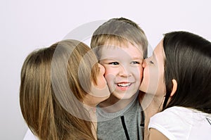 Two teens girls kissing little laughing boy