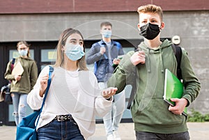 Two teens in protective masks walk along street
