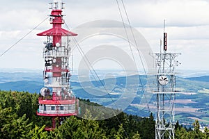 Two telecommunication towers with communication transmitters and aerials in forest
