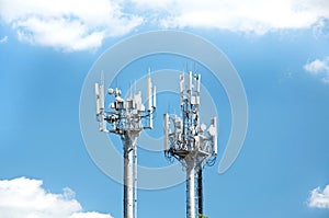 Two telecommunication towers with radio modules and antennas against a background of blue sky and clouds. Smart antennas transmit