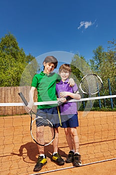 Two tennis winners standing next to the net