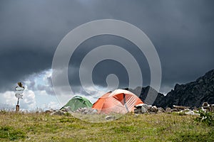 Two tents camping on summit with storm clouds above