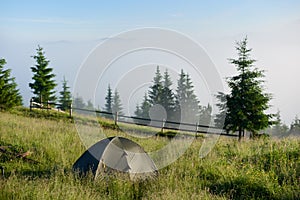 Two tents in the hikers camp in the mountains in sunny morning facing incredible rising fog from a valley