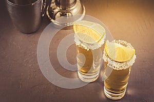 two Tequila shot with lime fruit/two Tequila shot with lime fruit on a dark stone background. Copyspace