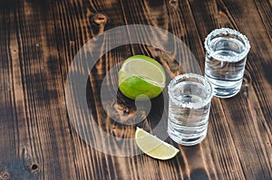 Two Tequila shots with lime slices and salt on wooden table/Tequila shots and lime slice on wooden table with Copy cpace. Top view