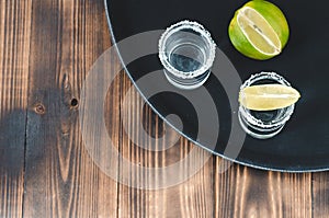 Two Tequila shots with lime slices and salt on wooden table/Tequila shots and lime slice on wooden table with Copy cpace. Top view