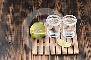 Two Tequila shots with lime slices and salt on wooden table/Tequila shots and lime slice on wooden table with Copy cpace. Top view