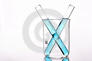 Two test tubes with blue acid standing in glass beaker on white background