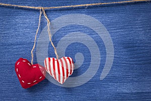 Two textile hearts over wooden wall