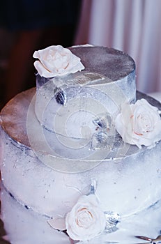 Two-tier cake decorated with silver glaze and white roses