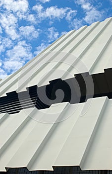 Two-tiered corrugated iron roof against cloudy sky