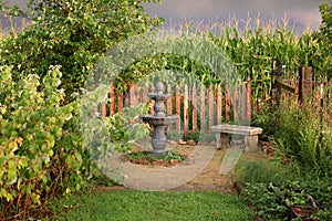 Two Tiered Water Fountain in Lush Green Garden by Stone Bench