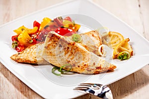 Two tilapia fish fillets on white plate photo