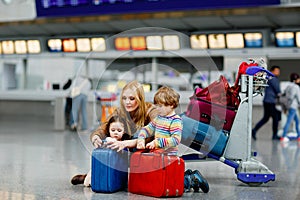 Two tired little kids, boy and girl, siblings and mother at the airport. Children, family traveling, going on vacation