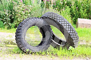 two tires from the car lie on the green grass. The concept of pollution of the environment and industrial industry that