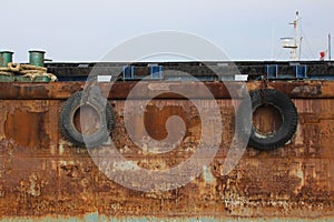 Close up tires on the rusted ship in the harbor