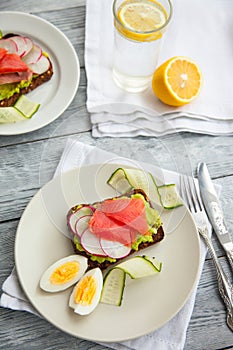 Two Toast sandwiches with Salmon, Avocado,eggs and cucumber on wooden board