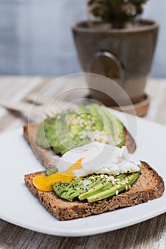 Two toasts with avocado, sesame and egg on a wooden table