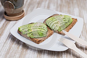 Two toasts with avocado and sesame on a wooden table