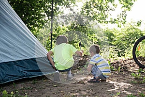 Two toddler boys hammering a spike for camping tent