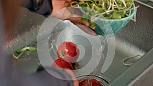 Two tomatoes being washed in sink, potential ingredient for a delicious recipe