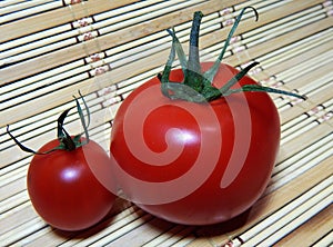 Two tomatoes large and small on a wooden napkin