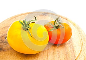 Two tomatoes on wooden cutting board