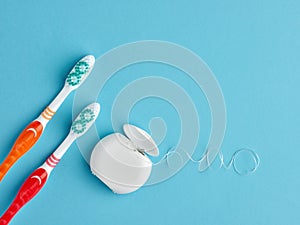 Two toothbrush and a box of dental floss on blue background