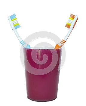 Two toothbrushes facing each other in a glass