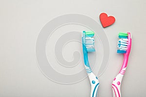 Two toothbrushes with heart on grey background. Man and woman teeth hygiene. Living together. Love concept
