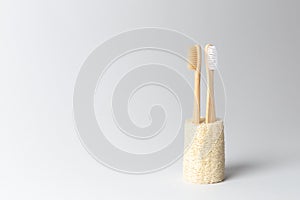 Two toothbrushes made of natural wood are inserted into the natural ecological loofah. on white background.