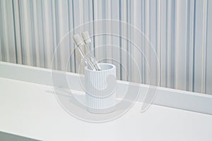 two toothbrushes in white white cup in bathroom on striped background