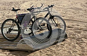 Two touring bikes on beach stand.