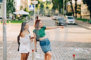 Two tourist friends consulting an online guide on a smart phone in the street