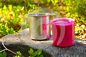 Two Touristic Cups metal and pink plastic with Tea on stone