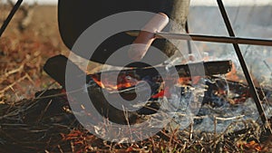 Two tourists beer are sitting by lifestyle bonfire hiking party close-up in nature camping silhouette sunlight sunset